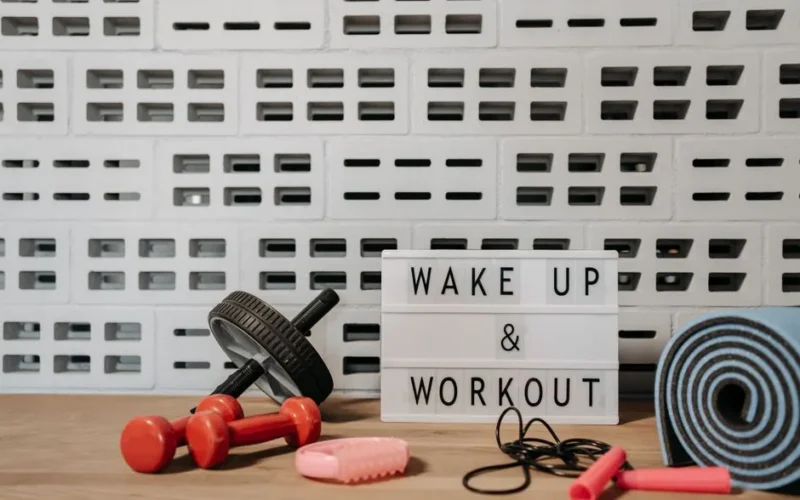 Fitness gear and motivational sign in home gym setup against a brick wall.