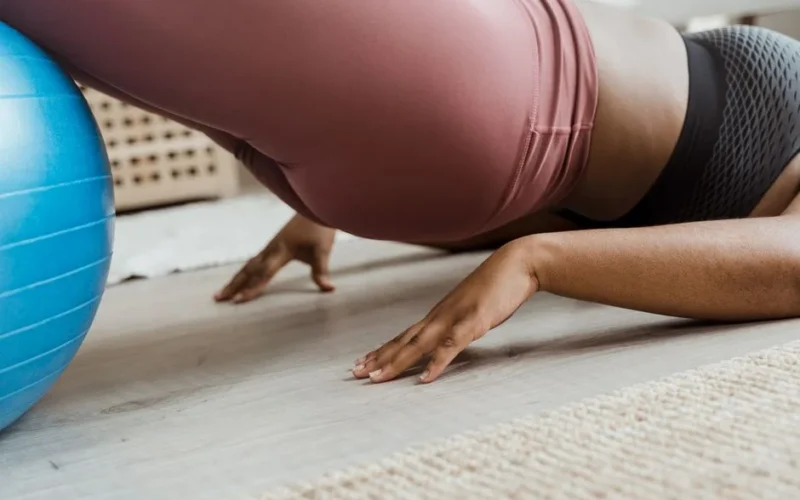 Close-up of a woman working out indoors using a fitness ball. Focus on balance and core strength.
