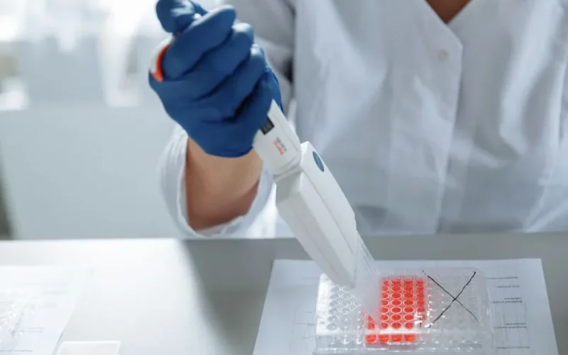 Close-up of a scientist using a pipette in a lab with a focus on sterile procedures.