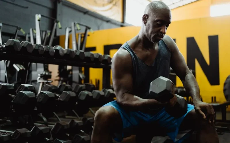 Focused man lifting weights in a gym, building strength and muscle.