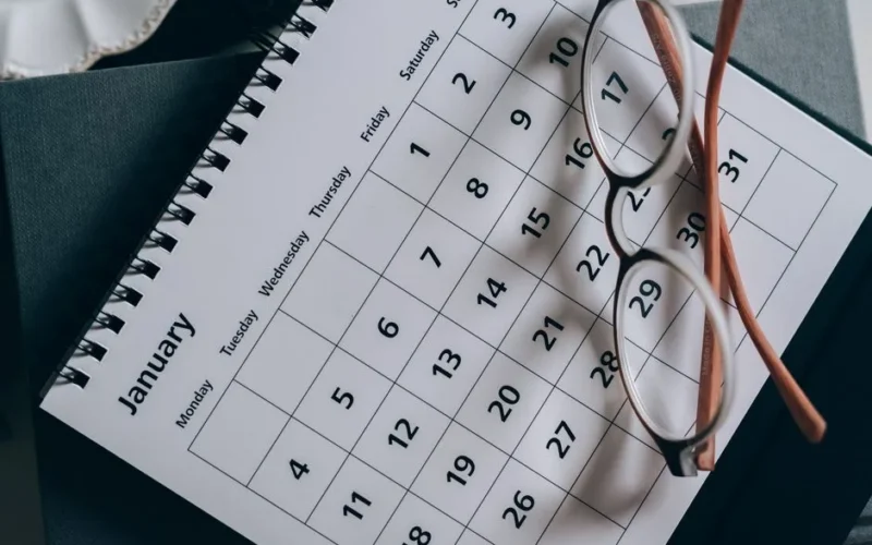 A close-up of a January calendar with eyeglasses on a table, emphasizing planning and organization.