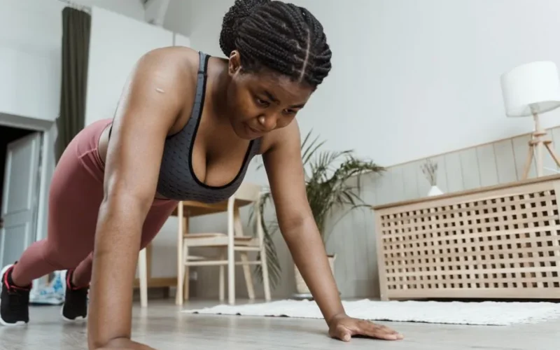 Plus-size woman performing push-ups indoors, emphasizing fitness and healthy living.