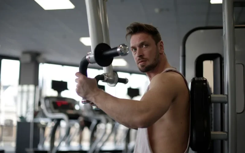 Focused man working out in a gym, showcasing biceps and determination.