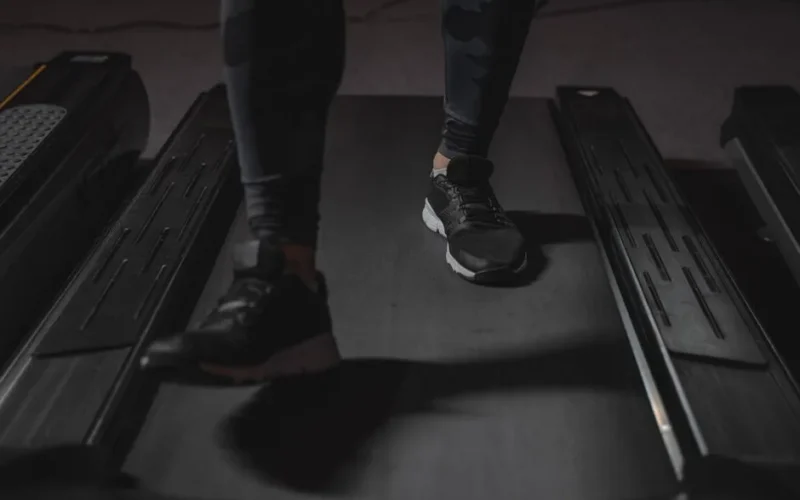 Feet running on treadmill in gym. Focus on black sneakers. Fitness and cardio exercise concept.