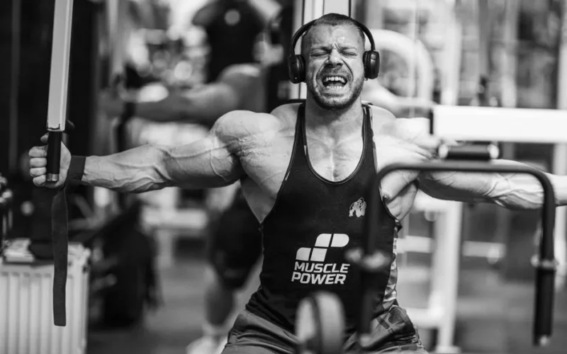 Muscular man intensely working out with gym equipment, showcasing strength and focus.