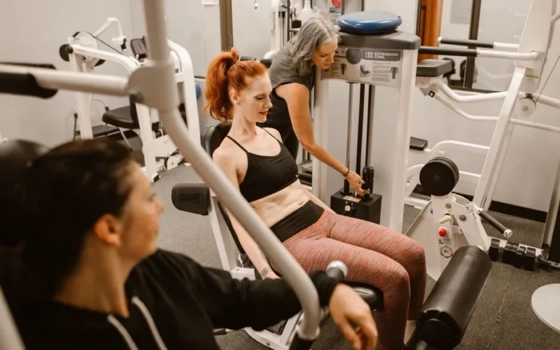 Women working out on gym equipment, promoting strength and fitness.